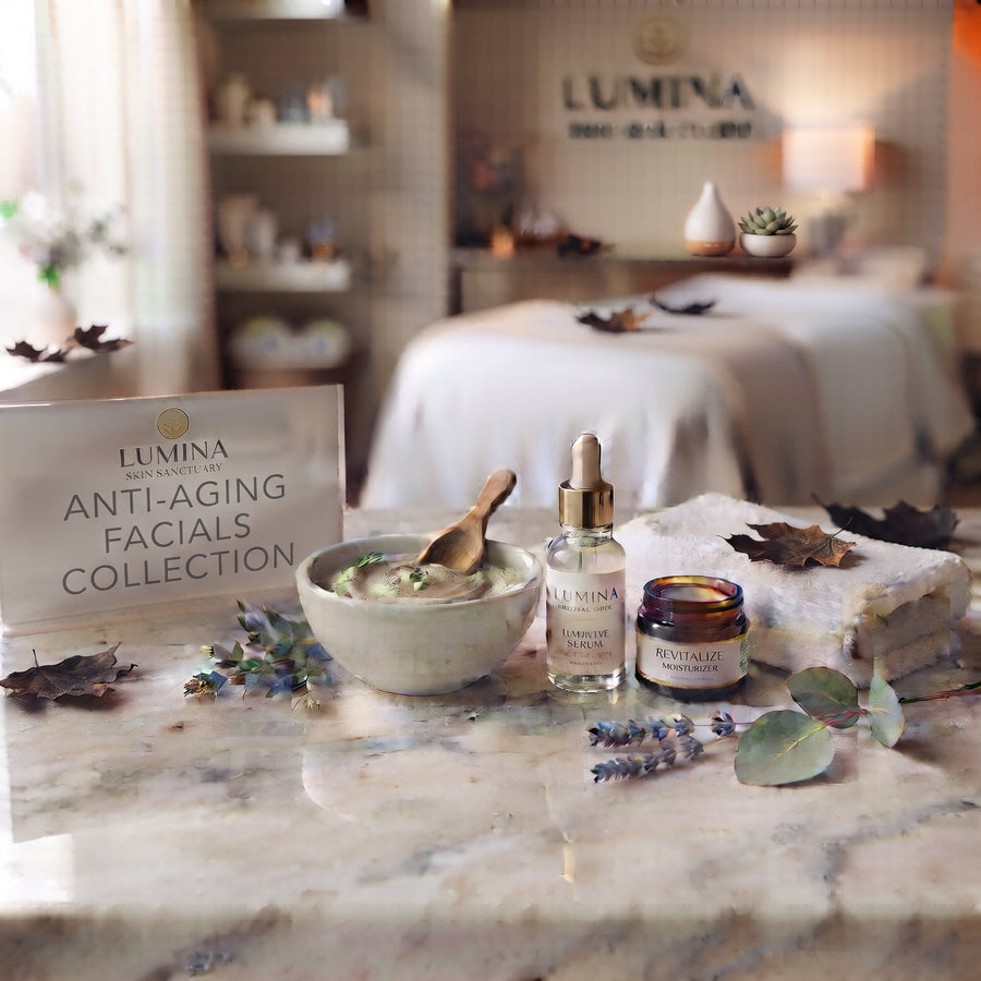 Lumina sign reading Anti-Aging Facials Collection beside a clay mask bowl, serum bottle, jar and folded towel on a marble counter, with a treatment bed behind, at Lumina Skin Sanctuary in Fort Myers, FL